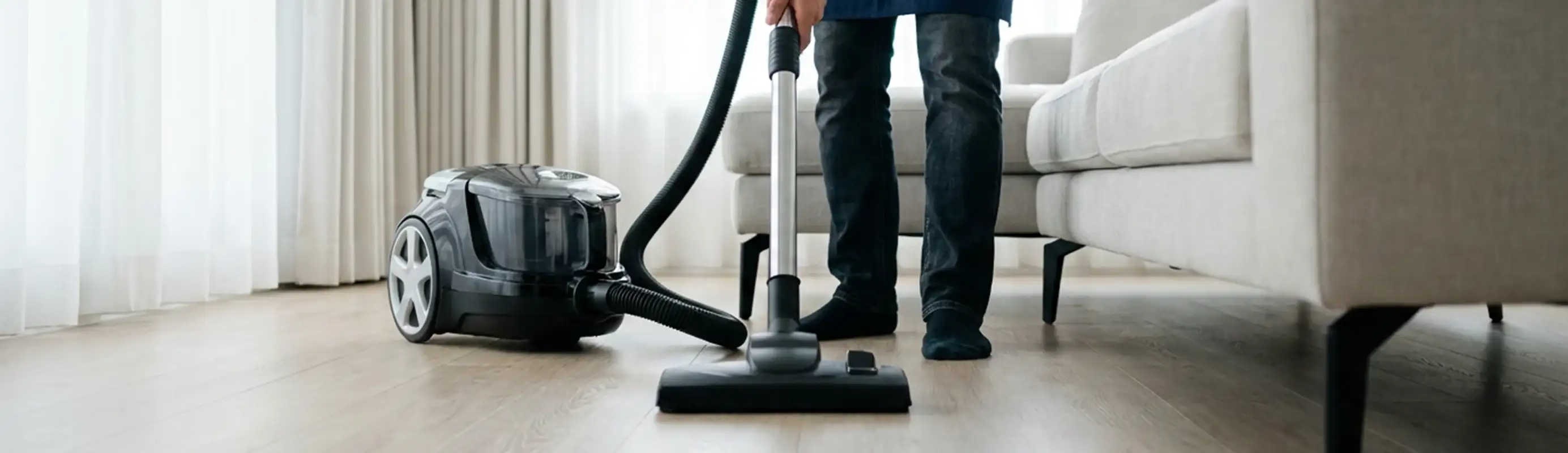 Professional house cleaner vacuuming a living room floor with a canister vacuum cleaner, Lincoln, NE.