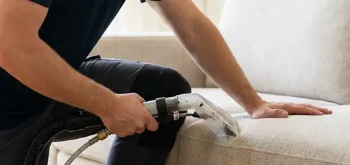 Professional upholstery cleaner deep-cleaning a fabric sofa with a handheld extraction tool, Lincoln, NE.